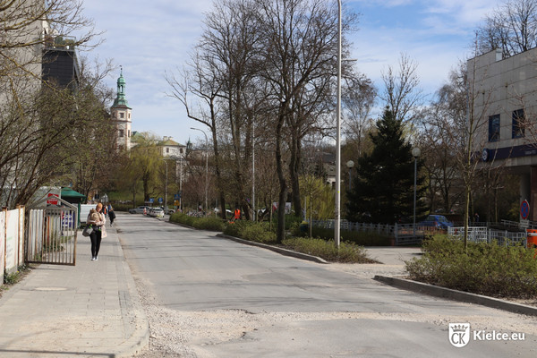 Ulica Solna. Po lewej stronie po chodniku idzie kobieta z dzieckiem. Po prawej stronie drzewa. Na drugim planie fragment dawnego Pałacu Biskupów Krakowskich.