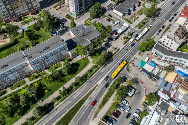zdjęcie z drona; przedstawia ulicę Seminaryjską, po której jedzie autobus komunikacji miejskiej. Po lewej bloki mieszkalne, po prawej plac targowy