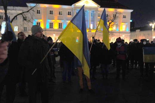 Mieszkańcy Kielc na Rynku z ukraińskimi flagami. W tle ratusz podświetlony na niebiesko-żółto
