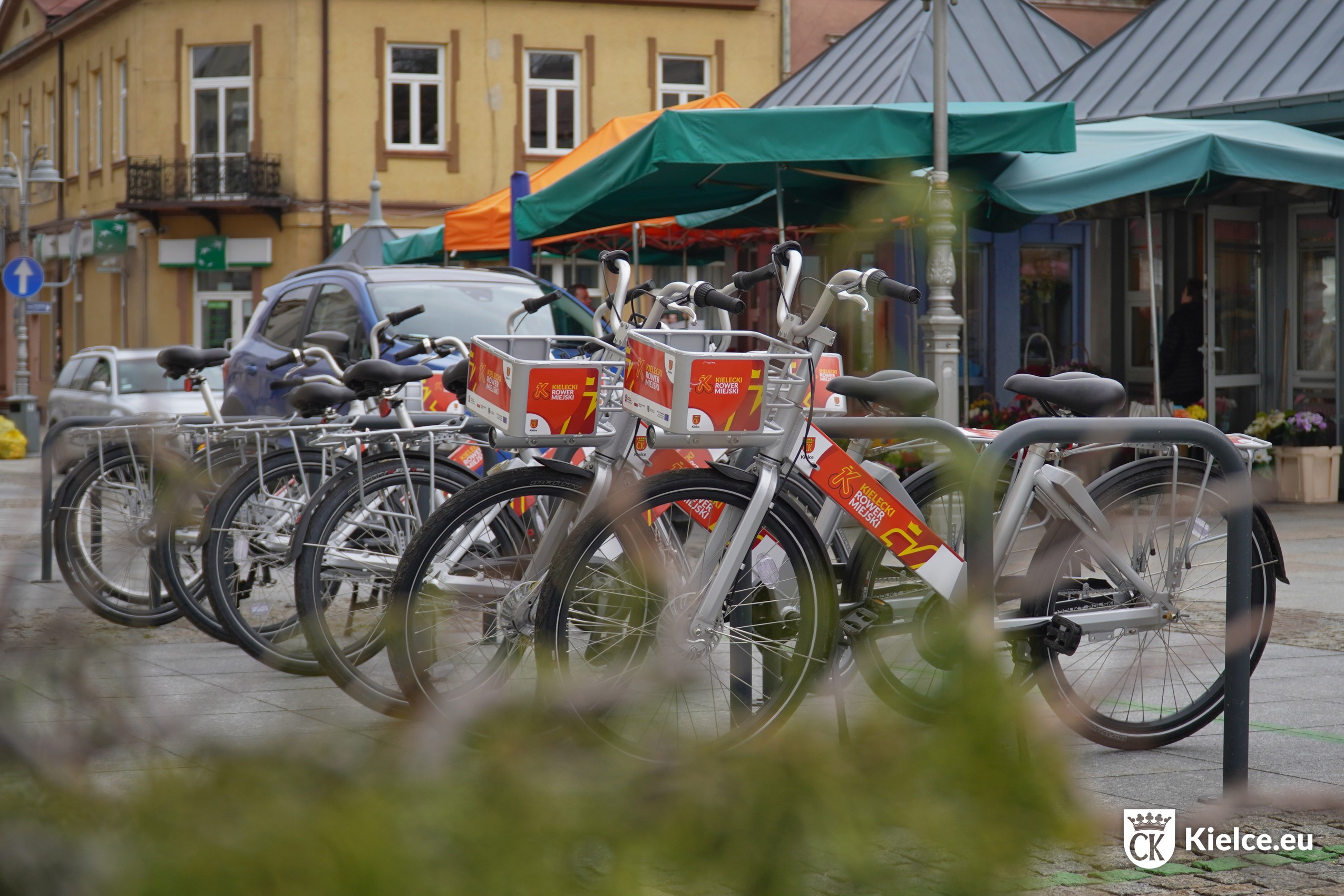 Kilka rowerów miejskich na stacji przy Rynku w okolicach kwiaciarni
