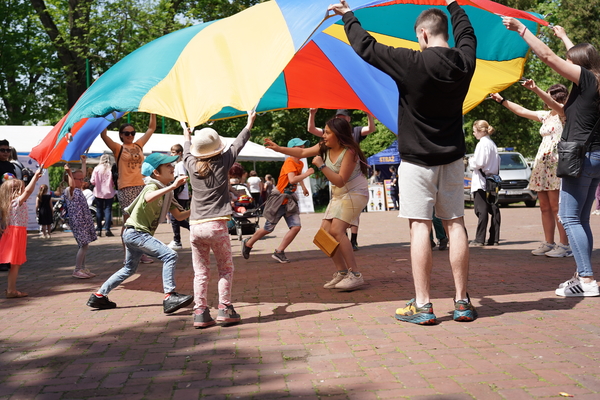Grupa osób bawiąca się kolorową chustą animacyjną